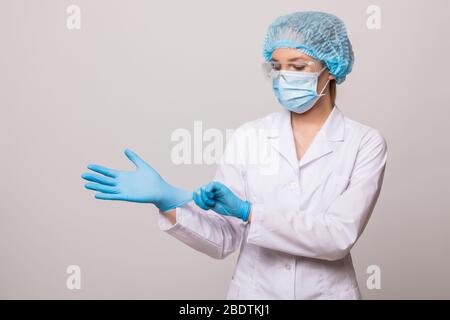 Jeune femme médecin en uniforme blanc portant des gants et masque Banque D'Images