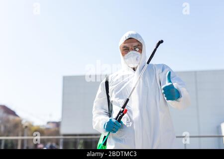 Désinfecteur dans un costume et un masque de protection, tenant les produits chimiques de désinfection à l'extérieur Banque D'Images