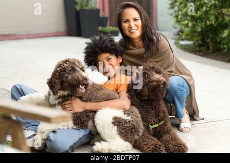 Mère et son fils rient et jouent avec leur chien. Banque D'Images