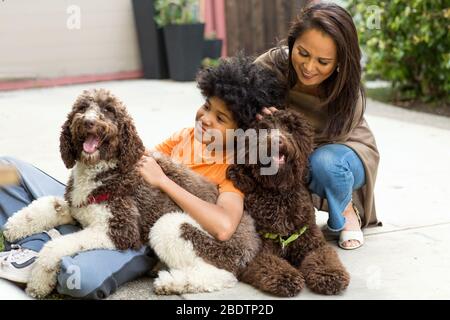 Mère et son fils rient et jouent avec leur chien. Banque D'Images