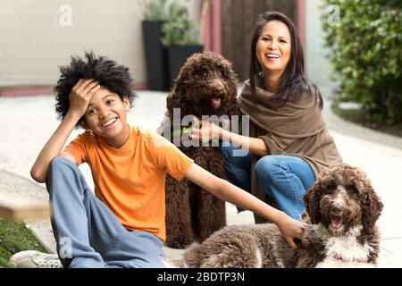 Mère et son fils rient et jouent avec leur chien. Banque D'Images