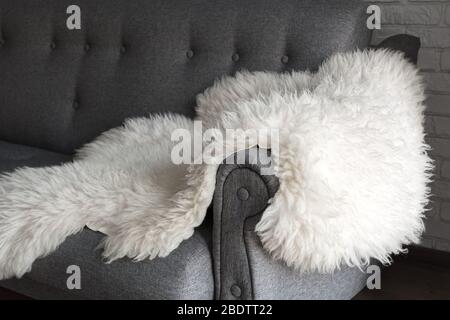 Peau de mouton blanche sur un canapé gris. Un endroit confortable pour se détendre dans l'appartement. Intérieur moderne de style scandinave Banque D'Images