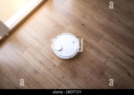 Robot-aspirateur sur le laminé. Vue de dessus. Nettoyage dans l'appartement. Banque D'Images