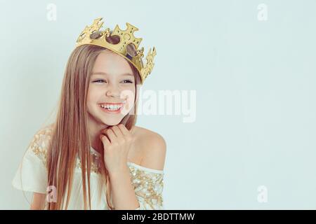 Mini Mons jeune fille heureuse avec un sourire mignon rire portant une couronne et une robe blanche sur les vacances regardant côté pupilles isolé vert arrière-plan Banque D'Images