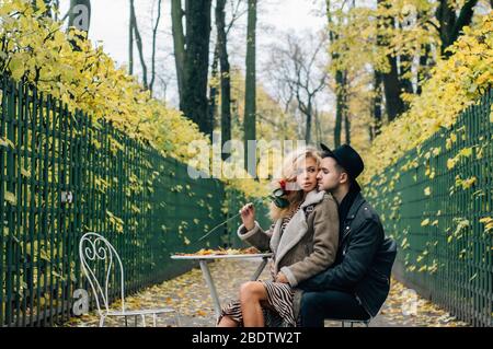 Couple siting sur chaise au centre du passage et embrassant, fille tient rouge rose dans la main Banque D'Images