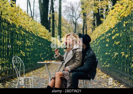 Couple siting sur chaise au centre du passage et embrassant, fille sent rose rouge Banque D'Images