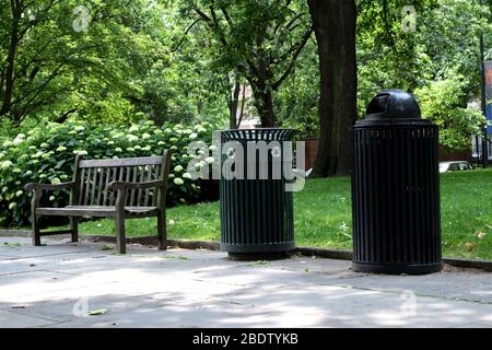 Banc vacant à côté de deux poubelles dans un parc public déserté. Le parc municipal est fermé en raison de la place de Covid-19 et de l'éloignement social. Gestion des déchets urbains Banque D'Images