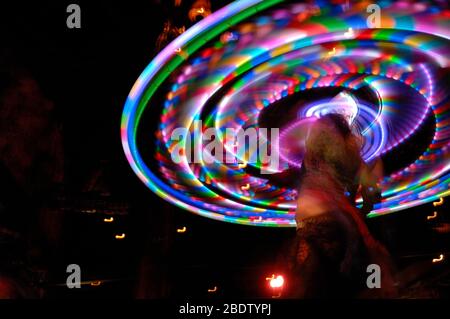 Les lumières Hoop Hula multicolores se sont tortillées dans le mouvement circulaire par Dancer en dentelle avec vitesse d'obturation lente, provoquant une photographie de flou intentionnelle Banque D'Images