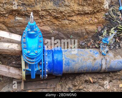 Nouveau papillon bleu sur tuyau d'eau souterrain de 300 mm. Pipeline en acier et PE dans l'excavation sous la route Banque D'Images