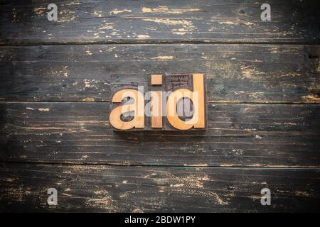 Le mot « AID » écrit en bois vintage typographie sur un fond rustique vintage. Banque D'Images
