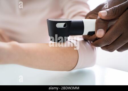 Médecin de la femme examinant la peau du patient de la femme avec le Dermatoscope en clinique Banque D'Images