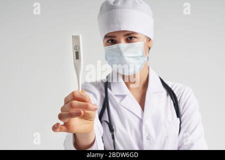 Jeune femme médecin montrant thermomètre sur fond blanc, studio tourné Banque D'Images