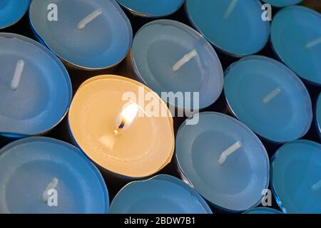 Gros plan des lampes à thé avec un éclairage. Une flamme orange chaude entre les bougies dans l'ombre bleue. Concept de Noël, de deuil ou de condoléances. Banque D'Images