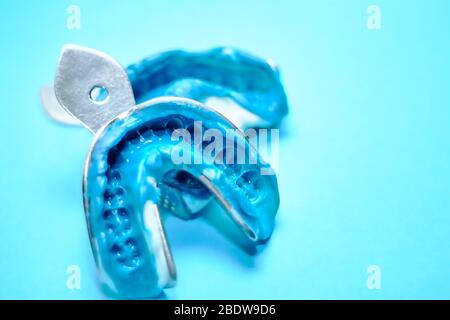 Deux impressions dentaires sur un fond bleu avec espace de copie. Moules dentaires à base de mâchoires supérieure et inférieure en silicone. Banque D'Images