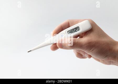 thermomètre médical maintenu dans une main masculine sur fond blanc Banque D'Images