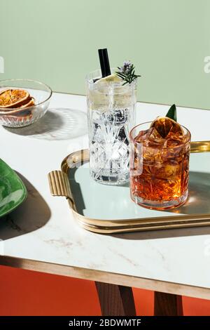 Gin tonique et cocktail Negroni, avec orange charré, tranche de citron et romarin fleuri, sur une petite table. Esthétique vintage avec filtre en étoile Banque D'Images