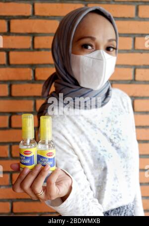 Deux bouteilles de désinfectant pour les mains qui sont détenues par une femme musulmane avec masque de protection (pas au centre). Banque D'Images
