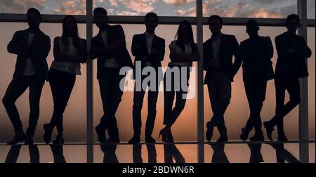 Silhouette d'une équipe entreprises debout à côté de la fenêtre du bureau Banque D'Images