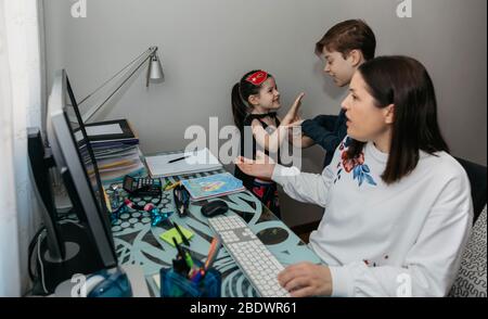 Femme travaillant de la maison avec ses enfants la plaisante Banque D'Images