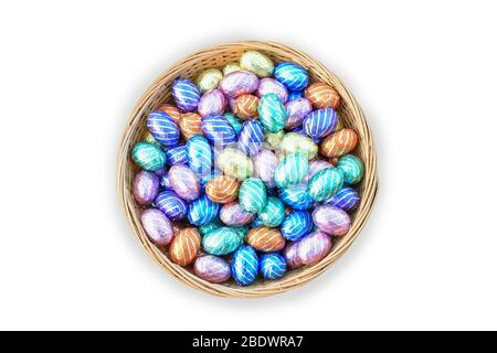 Oeufs de Pâques au chocolat coloré dans le panier isolé sur fond blanc. Banque D'Images