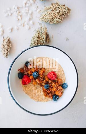 Porridge de flocons d'avoine dans un bol recouvert de bleuets frais, de canneberges et de granola croquante maison Banque D'Images