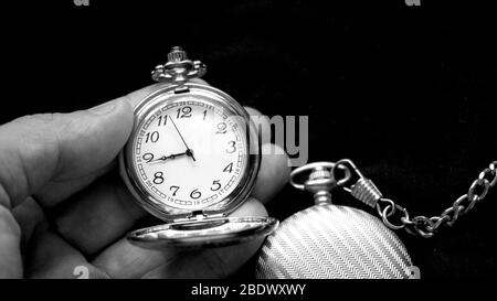Deux anciennes montres de poche anciennes une est tenue à la main. L'une est ouverte l'autre est fermée. Photographie noir et blanc Banque D'Images