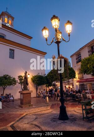 Les gens qui mangent sur une place pavée dans la vieille ville de Marbella, Marbella, Espagne. Banque D'Images