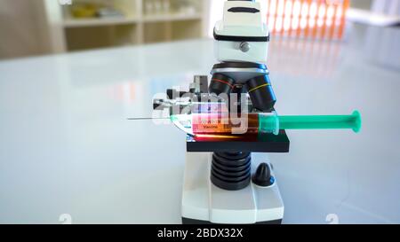 Regardez de plus près le microscope noir avec le vaccin contre le coronavirus à l'intérieur de la seringue Banque D'Images