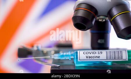 Examen plus étroit de la seringue de vaccin pour les vaccins contre le coronavirus COVID-19 trouvés sur le stade du microscope drapeau britannique Banque D'Images