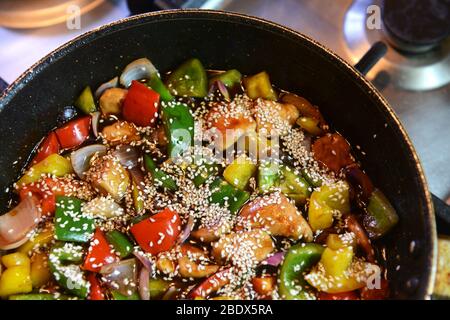 Sauté fraîchement préparé avec poulet et légumes, y compris oignons, poivrons rouge, jaune et vert dans un wok Banque D'Images