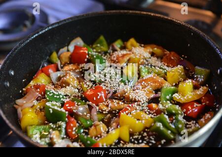 Sauté fraîchement préparé avec poulet et légumes, y compris oignons, poivrons rouge, jaune et vert dans un wok Banque D'Images