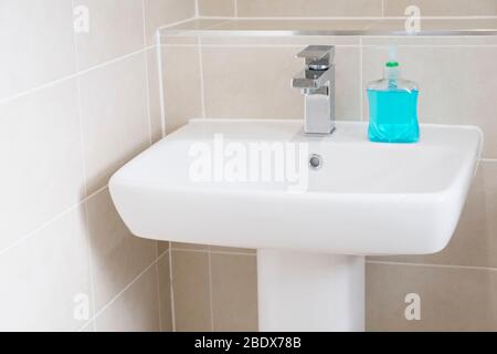 Lavage des mains anti-bactérien bleu sur le bassin pour prévenir le coronavirus et les autres germes ou virus Banque D'Images
