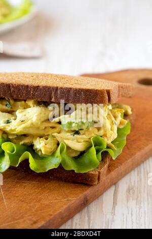 Sandwich au poulet au couronnement fait maison sur un panneau rustique en bois sur fond blanc en bois, vue à bas angle. Banque D'Images