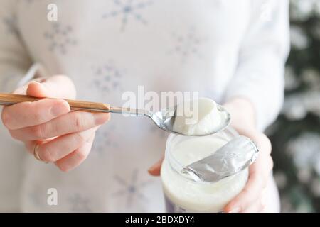 Cuillère avec yaourt thermostat dans la main d'une fille Banque D'Images