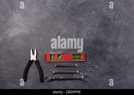 Différents outils à main pour la construction, la réparation- pince, l'outil de niveau, la clé sur fond gris. Vue de dessus, floy. Espace libre. Espace de copie. Banque D'Images