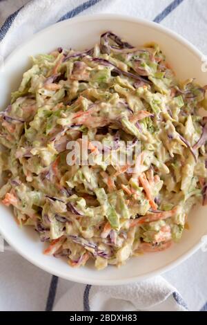 Creamy Broccoli Slaw maison dans un bol blanc sur tissu, vue sur le dessus. Plat, vue de dessus. Gros plan. Banque D'Images