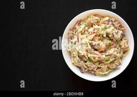 Creamy Broccoli Slaw maison dans un bol blanc sur fond noir, vue d'en haut. Plat, vue supérieure, en hauteur. Espace de copie. Banque D'Images