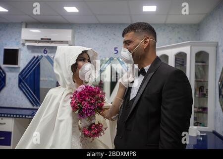 Bethléem, camp de réfugiés palestiniens de Deheisheh près de la ville de Bethléem, en Cisjordanie. 10 avril 2020. La mariée palestinienne, Shima'al-Titi, ajuste le masque facial de son marié, Ishaq Mulleh, avant de quitter le salon de beauté dans le camp de réfugiés palestinien Deheisheh près de la ville de Bethléem, en Cisjordanie, le 10 avril 2020. Porter des masques et des gants comme mesures préventives, le couple a célébré son mariage lors de l'éclosion de COVID-19. Crédit: Luay Sababa/Xinhua/Alay Live News Banque D'Images