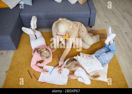 Grand-mère assis à l'étage et s'attirant avec ses deux petites-filles dans le salon Banque D'Images