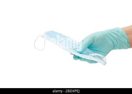 Main de médecin femelle dans un gant en latex contenant un masque de protection médicale sur un support isolé blanc. Équipement de protection individuelle contre le virus Banque D'Images