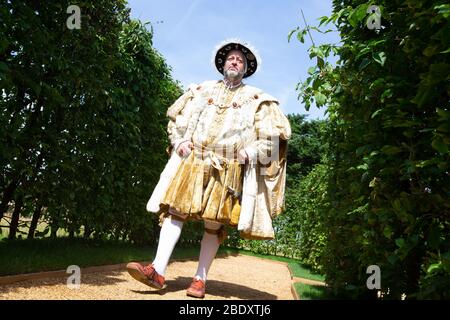 Un acteur, habillé comme le roi Henry le huitième, déstronit un chemin dans le domaine du palais de Hampton court. Banque D'Images