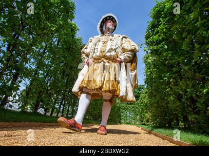 Un acteur, habillé comme le roi Henry le huitième, déstronit un chemin dans le domaine du palais de Hampton court. Banque D'Images