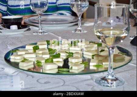 Cadre élégant à la table du restaurant, gros plan de verres à vin blanc prêts à la dégustation à côté d'une assiette miroir avec des tranches de mozzarella fraîches Banque D'Images
