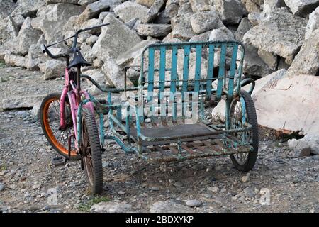 Une moto rose robuste avec chariot peint en bleu stationné près d'une pile de pierre en béton. Banque D'Images