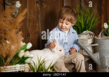 Un merveilleux petit garçon jouant avec un lapin de Pâques dans une herbe verte Banque D'Images