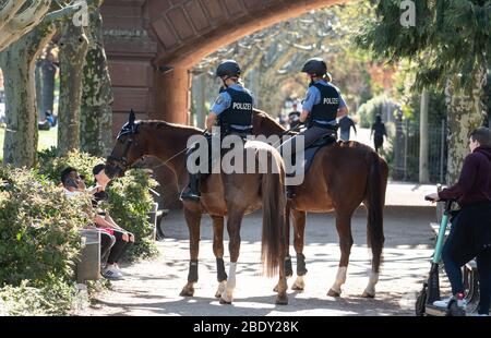 10 avril 2020, Hessen, Francfort-sur-le-Main : Deux policiers parlent à trois jeunes hommes (l) qui sont assis ensemble sur un banc tout en faisant monter leurs chevaux le long de la rive nord de la rivière Main pour vérifier que l'interdiction de contact, qui est toujours en place en raison de la pandémie de Corona, est observée. Photo: Frank Rumpenhorst/dpa Banque D'Images