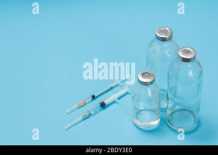 Flacons en verre pour la médecine liquide et seringues en plastique à injecter sur fond bleu. Vue de dessus. Concept de santé et de médecine. Banque D'Images