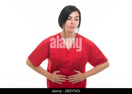 Portrait de jeune infirmière féminine séduisante tenant l'estomac comme mal isolé sur fond blanc avec espace de copie zone publicitaire Banque D'Images