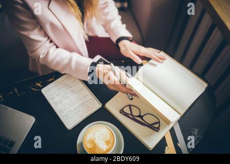 Travailler confortablement dans un café. Femme freelance feuilletant les pages d'un journal dans un café. Jolie femme à boire du café au restaurant Banque D'Images