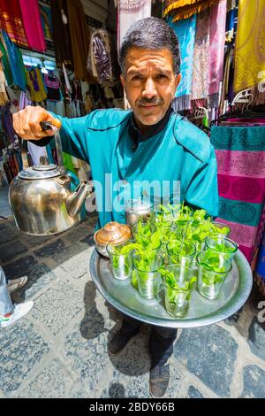 Homme qui verse du thé à la menthe à la médina. Banque D'Images